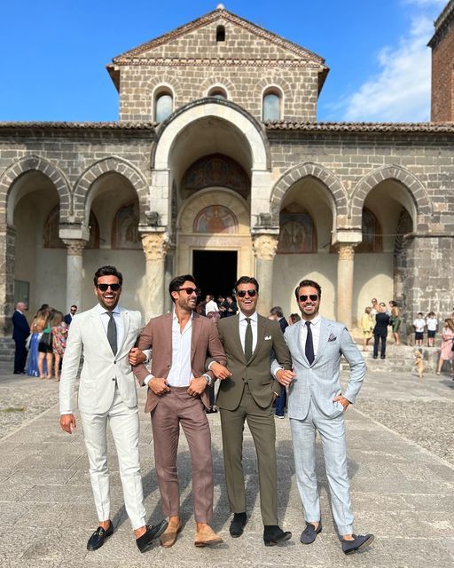 Quatre invités en costumes clairs devant l'église