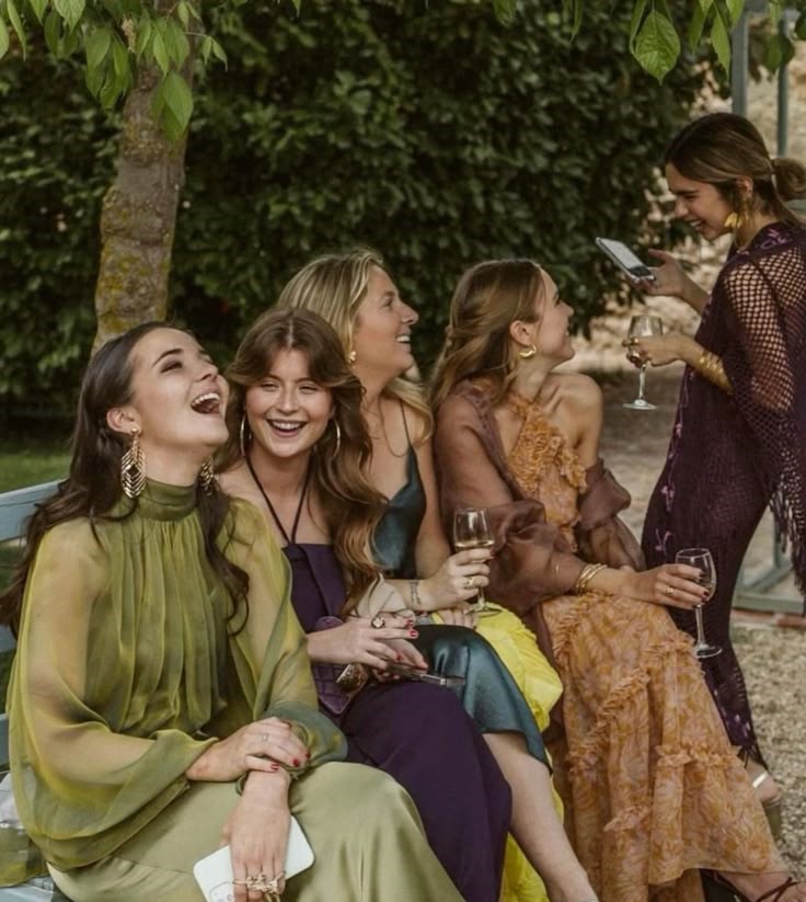 Invitées en robes colorées riant ensemble au jardin